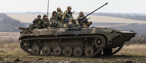 Ukrainische Soldaten sitzen während eines Militärtrainings auf einem sogenannten APC, einem gepanzerte Mannschaftstransportwagen.