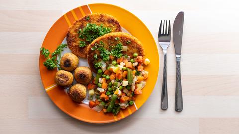 Falafel, vegane Schnitzel und Gemüse liegen garniert mit Petersilie auf einem Teller