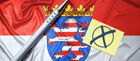 Fahne des deutschen Bundeslandes Hessen mit Zettel, Wahlkreuz und Kugelschreiber