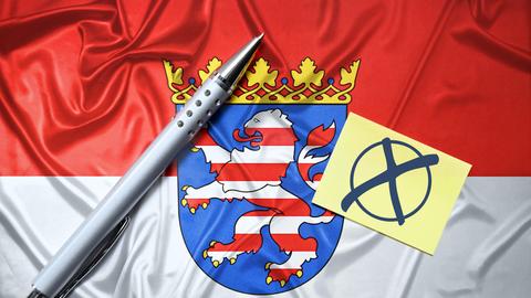 Fahne des deutschen Bundeslandes Hessen mit Zettel, Wahlkreuz und Kugelschreiber