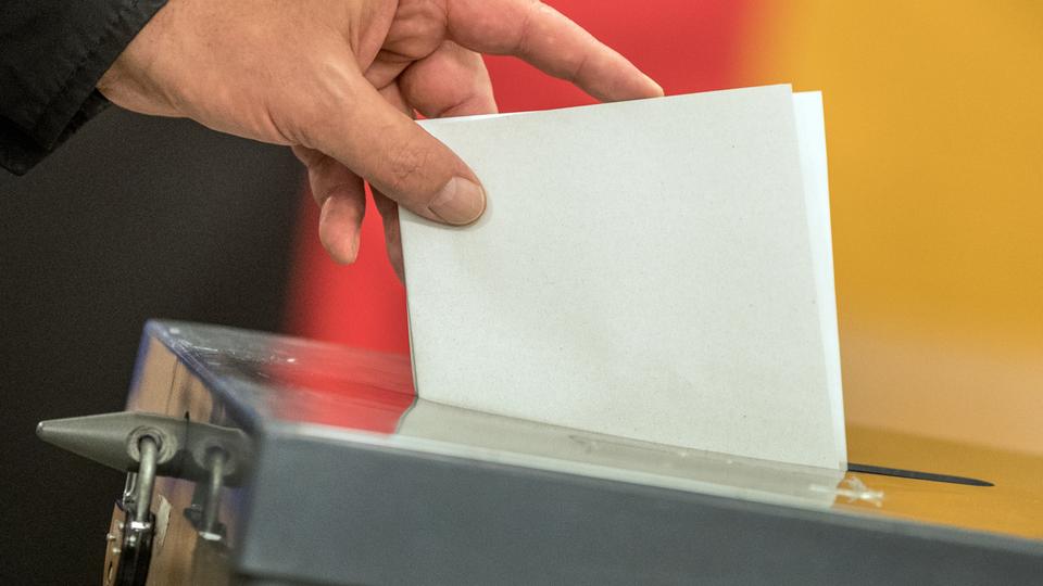 Ein Stimmzettel wird in eine Wahlurne gesteckt