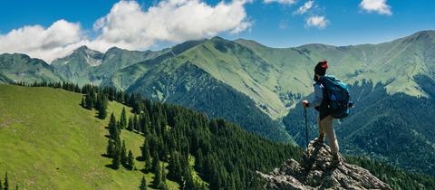 Mann in Wanderausrüstung steht auf einem Berg