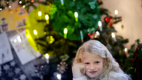 Kind sitzt vorm Weihnachtsbaum