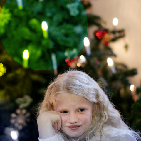 Kind sitzt vorm Weihnachtsbaum