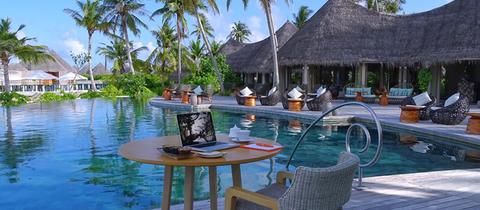 Tisch mit Laptop vor einem Pool