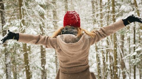 Frau breitet Arme aus vor Winterwald