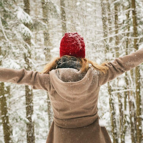 Frau breitet Arme aus vor Winterwald