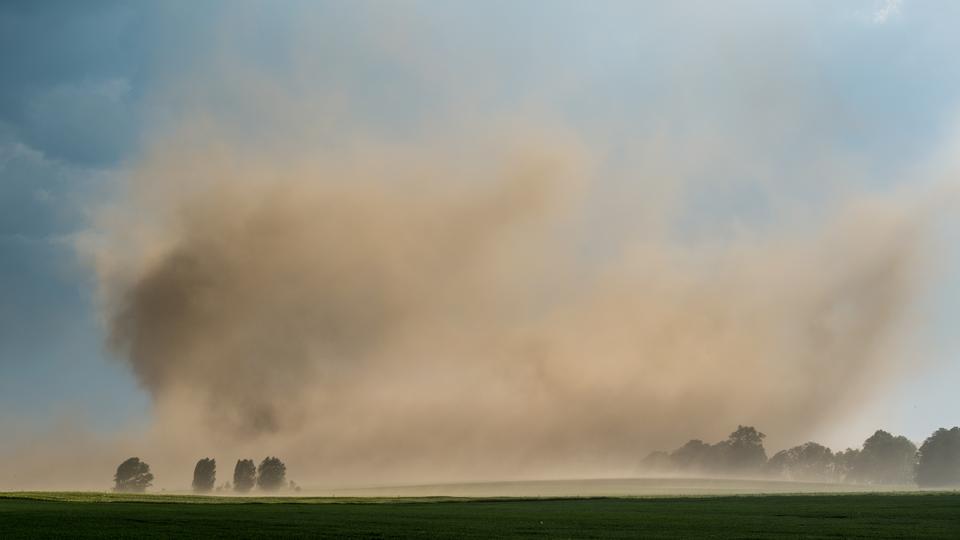 Sturm wirbelt trockenen Ackerboden eines Feldes in Brandenburg auf  